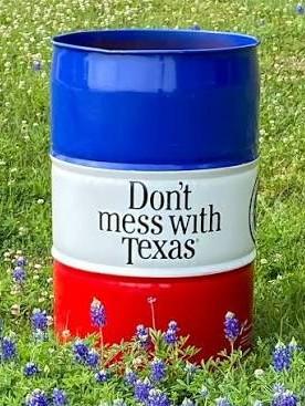 Red, white, and blue 55-gallon barrel surrounded by Texas bluebonnet wildflowers